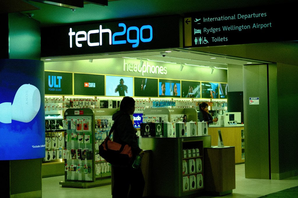 Entrance of tech2go store at the airport, featuring a variety of headphones and tech accessories on display.